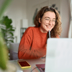 woman smiling with pen in hand near computer screen discussing pensions
